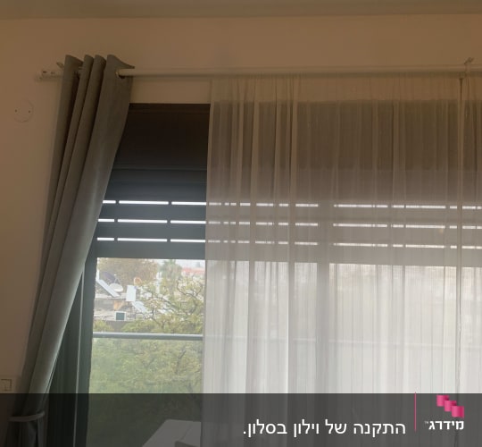 וילון תלוי על מוט מעל חלון זכוכית